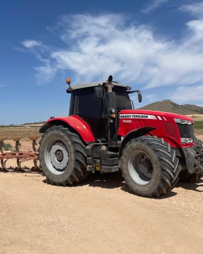 Un tractor rojo circulando por un camino de tierra.